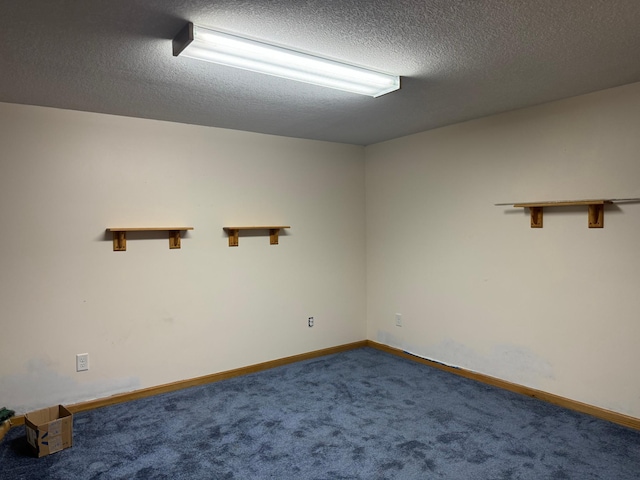 empty room with baseboards, dark colored carpet, and a textured ceiling