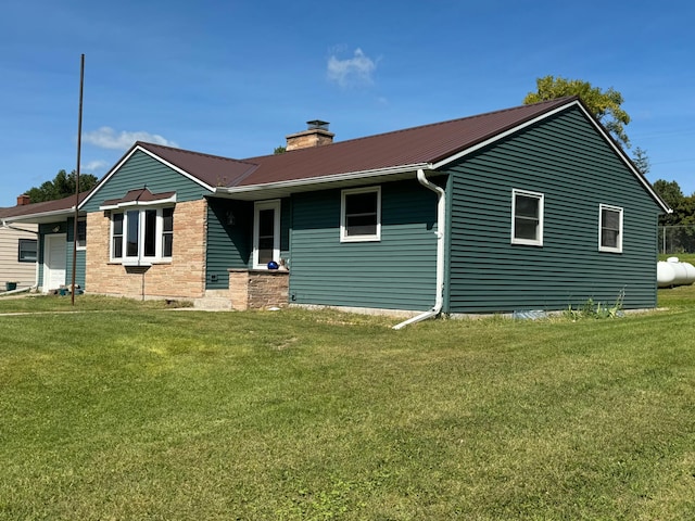 ranch-style house with metal roof, a chimney, and a front yard