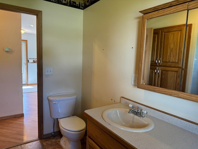 bathroom featuring toilet, vanity, and baseboards