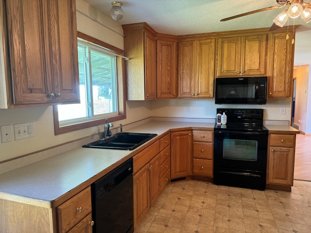 kitchen with light floors, a sink, black appliances, light countertops, and brown cabinets