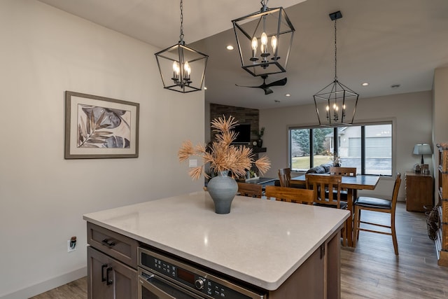 kitchen with a kitchen island, pendant lighting, wood-type flooring, and oven