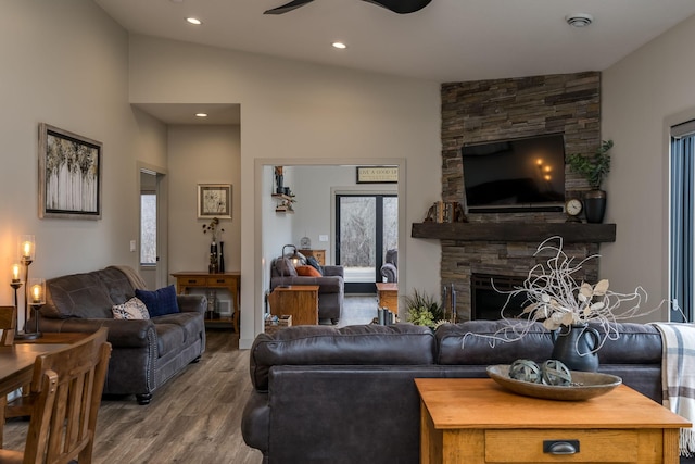 living room featuring hardwood / wood-style flooring, a stone fireplace, ceiling fan, plenty of natural light, and vaulted ceiling