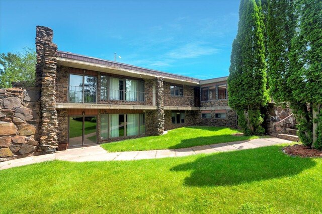 rear view of house with a balcony and a lawn