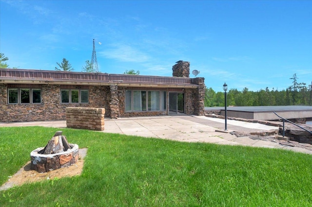 back of property featuring a yard, a fire pit, and a patio