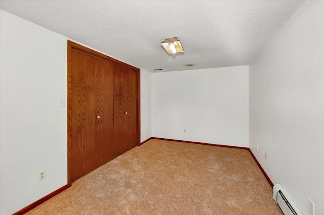 unfurnished bedroom featuring a baseboard heating unit, light carpet, a textured ceiling, and a closet