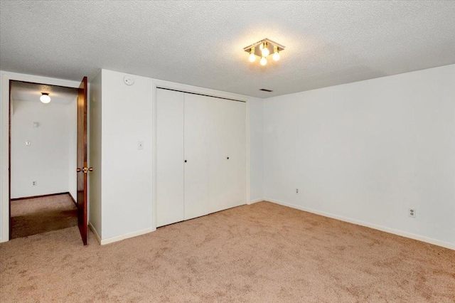 unfurnished bedroom featuring light colored carpet, a closet, and a textured ceiling