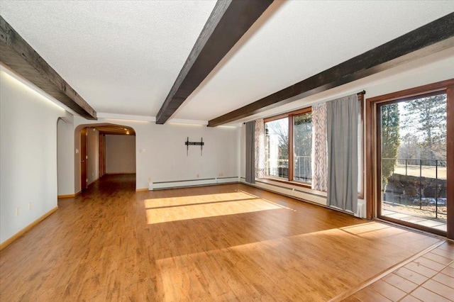 unfurnished living room featuring baseboard heating, plenty of natural light, a textured ceiling, and light wood-type flooring