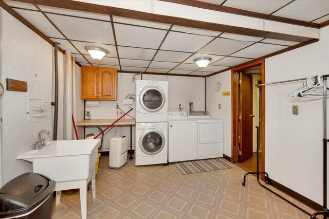 clothes washing area with cabinets, stacked washing maching and dryer, and washing machine and clothes dryer