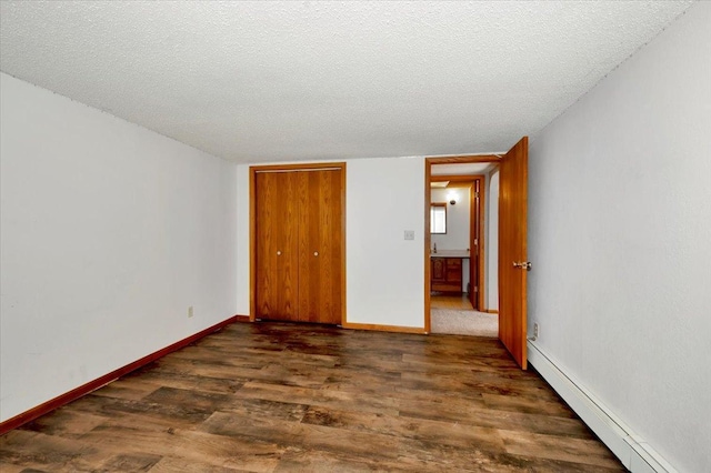 unfurnished bedroom featuring a baseboard radiator, dark wood-type flooring, a textured ceiling, and a closet