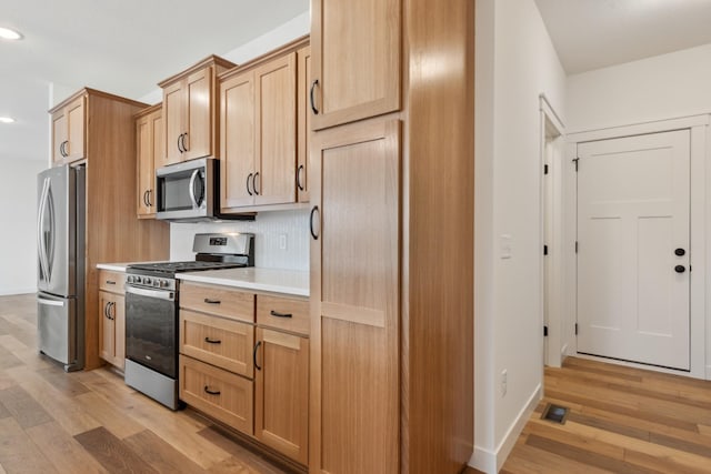 kitchen with appliances with stainless steel finishes, light brown cabinetry, and light hardwood / wood-style flooring