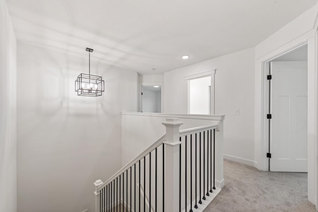 hallway with light colored carpet and a notable chandelier