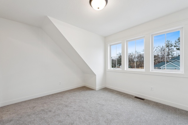 spare room featuring light colored carpet and vaulted ceiling