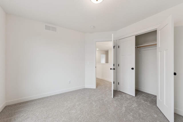 unfurnished bedroom with light carpet and a closet