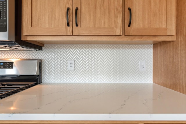 kitchen featuring stove, tasteful backsplash, and light stone counters