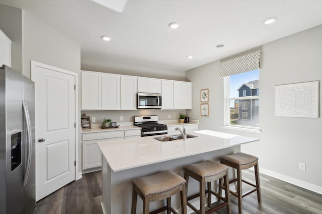 kitchen with white cabinetry, sink, dark wood-type flooring, a center island with sink, and appliances with stainless steel finishes