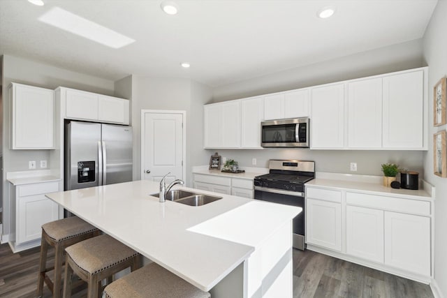 kitchen with white cabinets, appliances with stainless steel finishes, a center island with sink, and sink