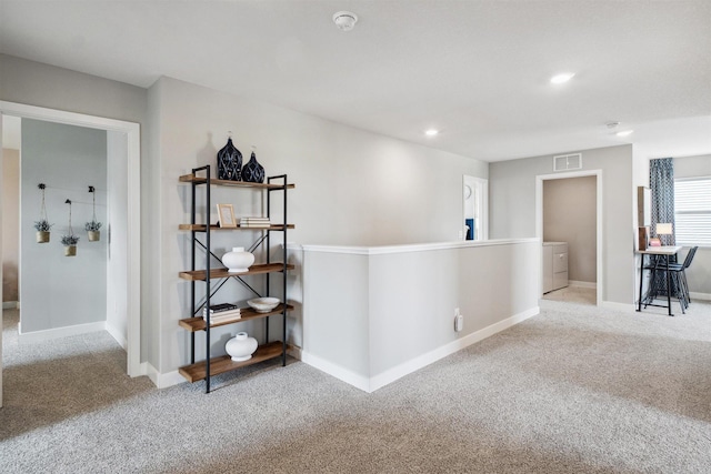 hall with washer / clothes dryer and light carpet