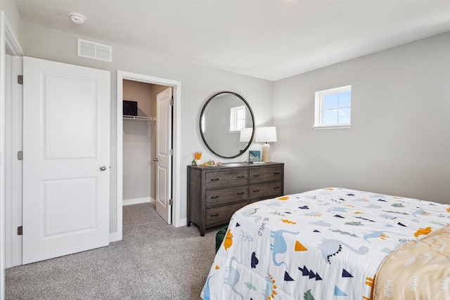 carpeted bedroom with a walk in closet and a closet