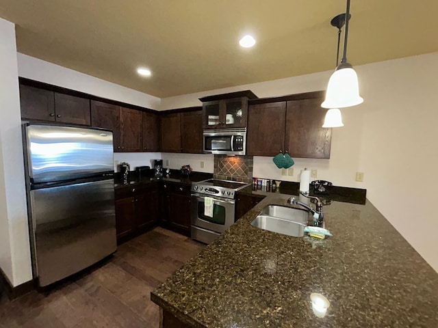 kitchen featuring decorative light fixtures, dark hardwood / wood-style floors, appliances with stainless steel finishes, sink, and dark stone countertops