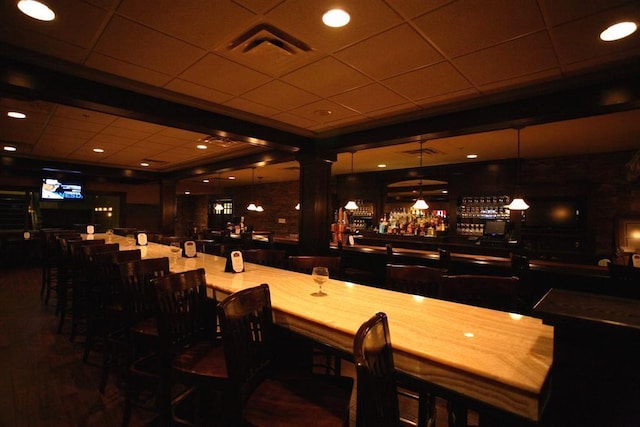 bar featuring a drop ceiling and hanging light fixtures