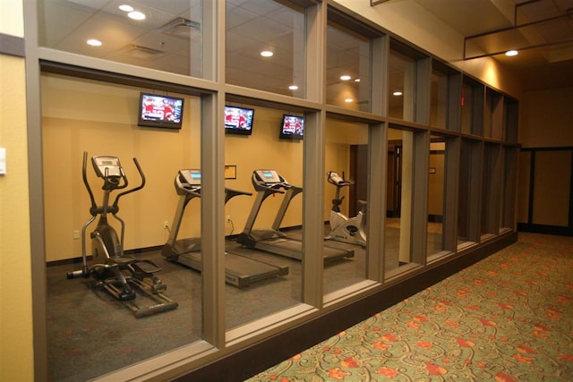 workout area with dark carpet and a paneled ceiling