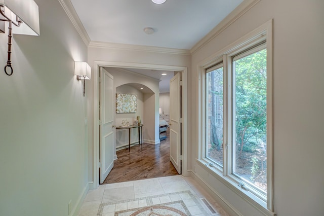 corridor featuring ornamental molding, plenty of natural light, and light hardwood / wood-style flooring