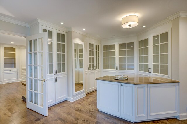 kitchen with ornamental molding, french doors, hardwood / wood-style flooring, and white cabinets