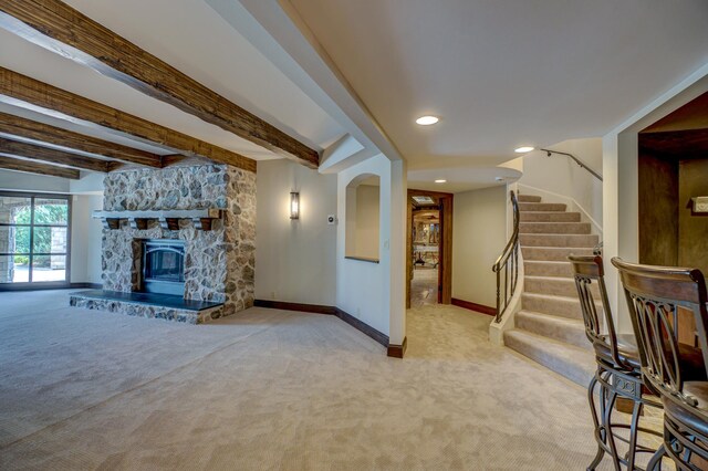 unfurnished living room featuring a fireplace, light carpet, and beam ceiling