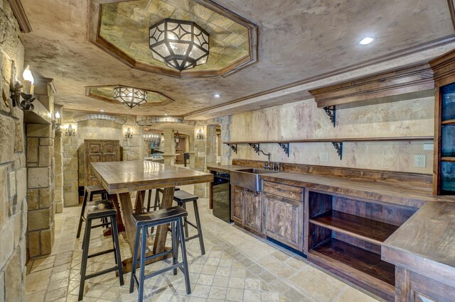 kitchen featuring butcher block countertops, a tray ceiling, dishwasher, and sink