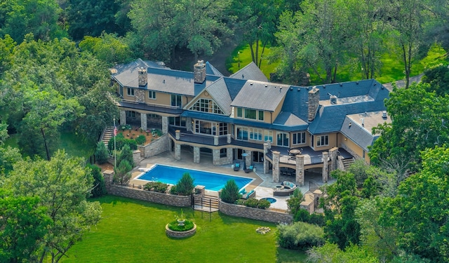 rear view of house featuring a yard, a chimney, stairway, a patio area, and a fire pit