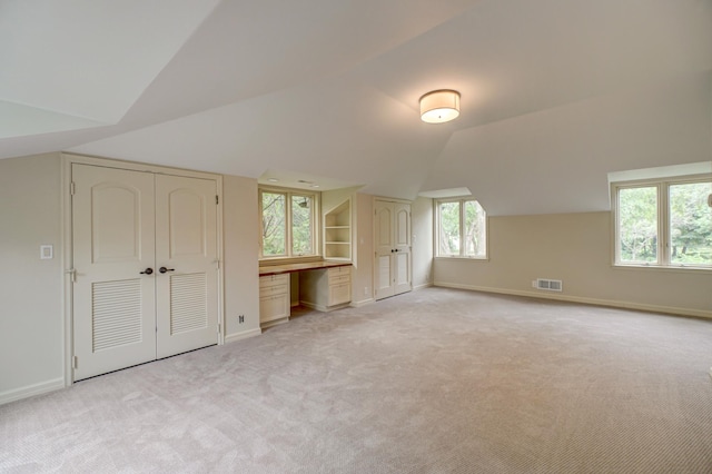 additional living space featuring lofted ceiling and light colored carpet