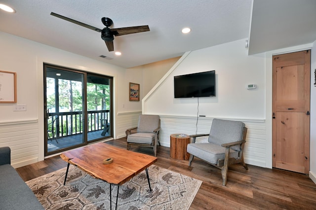 living room with a textured ceiling, ceiling fan, and dark hardwood / wood-style floors