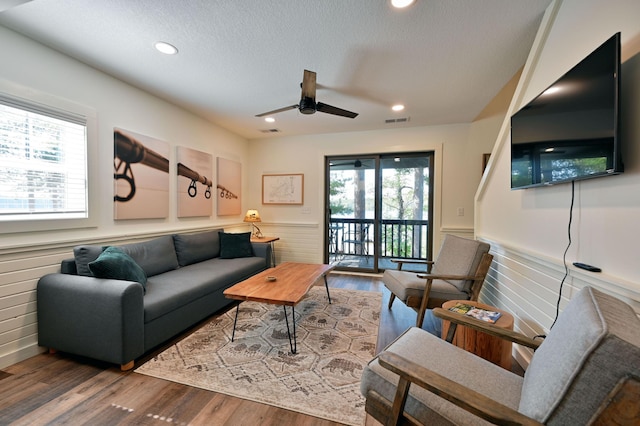 living room featuring ceiling fan, a textured ceiling, and hardwood / wood-style flooring