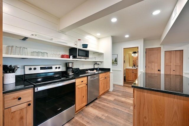 kitchen featuring appliances with stainless steel finishes, light hardwood / wood-style floors, dark stone counters, and sink