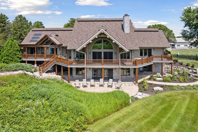 rear view of property with a patio, a lawn, and a wooden deck