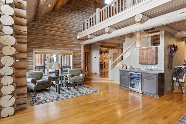 living room with beam ceiling, wine cooler, light hardwood / wood-style floors, bar area, and high vaulted ceiling