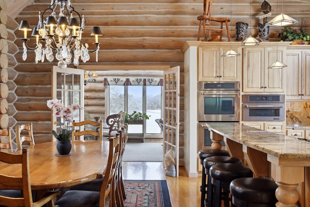 dining area with a notable chandelier, log walls, and light hardwood / wood-style floors