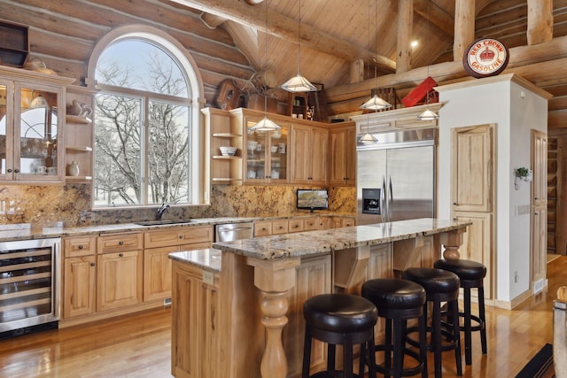 kitchen featuring stainless steel appliances, a kitchen island, vaulted ceiling with beams, light stone counters, and beverage cooler