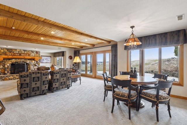 carpeted dining area with beam ceiling, wood ceiling, and a fireplace