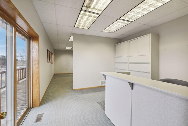 interior space featuring a paneled ceiling and light colored carpet