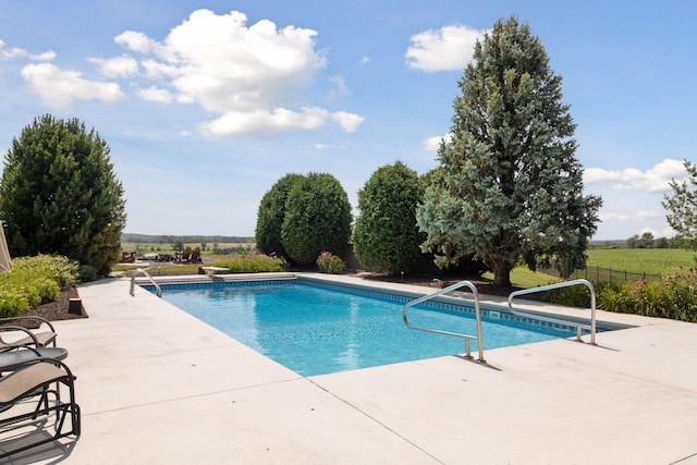 view of swimming pool featuring a rural view and a patio area