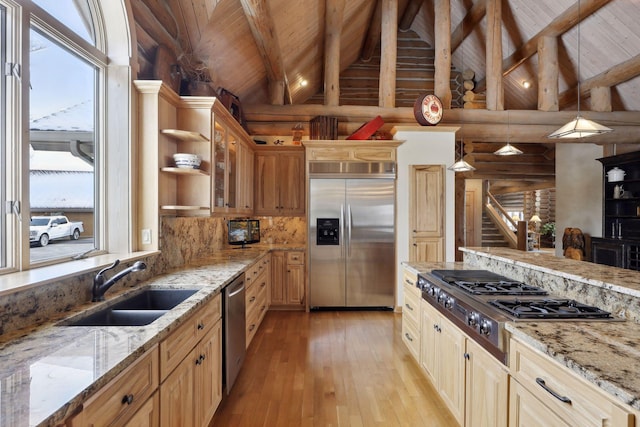 kitchen with hanging light fixtures, appliances with stainless steel finishes, sink, and light stone countertops