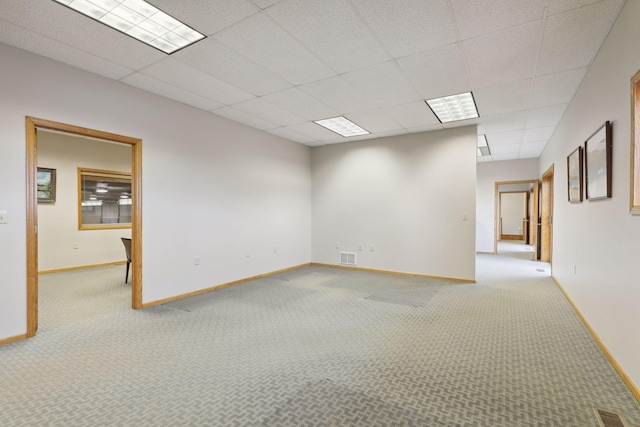 unfurnished room featuring a paneled ceiling and light carpet