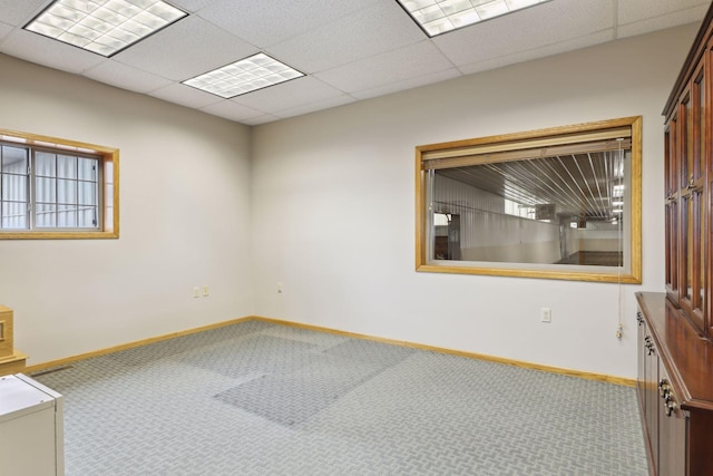 carpeted empty room featuring a paneled ceiling