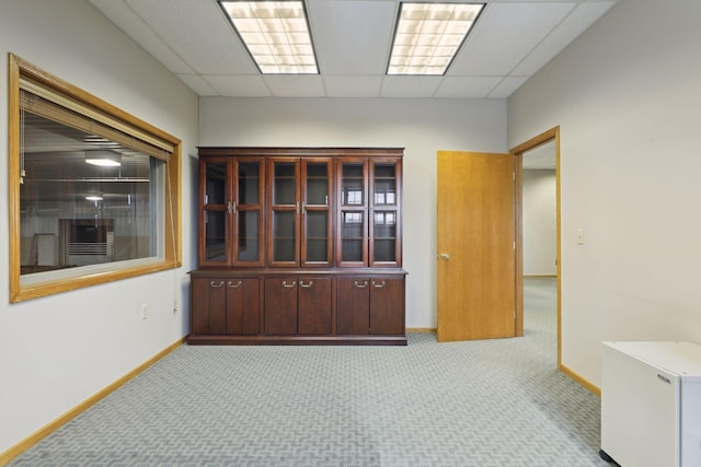 carpeted empty room featuring a drop ceiling