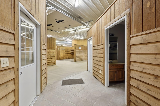 corridor with wood walls and light tile patterned floors