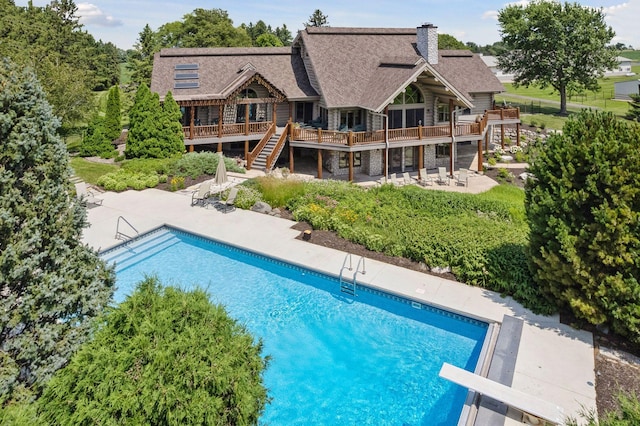 view of swimming pool with a patio area, a deck, and a diving board