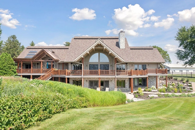 back of property with a wooden deck and a lawn