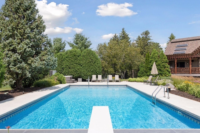 view of swimming pool featuring a diving board and a patio area