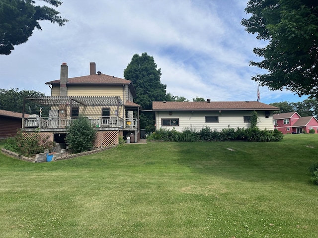 rear view of property featuring a wooden deck and a lawn